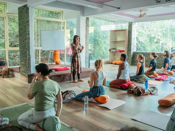 Woman in a focused yoga pose on a mat in a spacious studio.